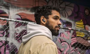 Mann med hettegenser som lytter med Bose-ørepropper med graffitibakgrunn