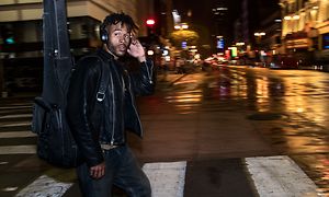 Ung mann krysser gaten med svarte Bose-hodetelefoner