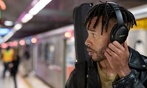 Ung mann på t-banestasjonen med svarte Bose-hodetelefoner