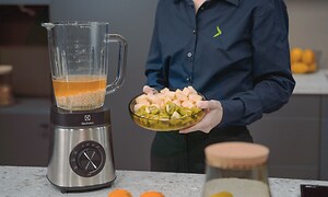 SDA - Blender - A woman holding a plate of vegetables next to a blender