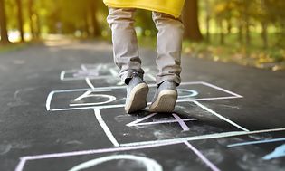 Closeup of little boy's legs and hopscotch drawn on asphalt