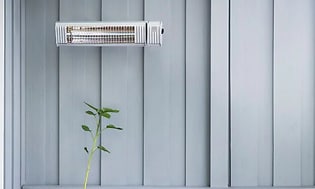 Veggmontert terassevarmer over grønn plante og sofa