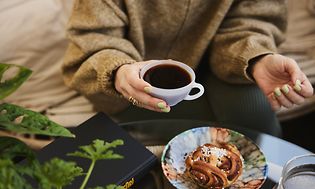 Kvinne som nyter kaffekopp og bakverk