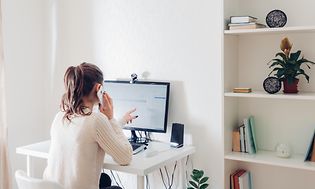 Kvinne på hjemmekontor foran PC med eksternt webkamera