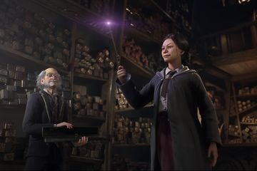 Skjermbilde fra spillet Hogwarts Legacy med en ung kvinnelig karakter som viser kunstner med tryllestav foran en eldre mann
