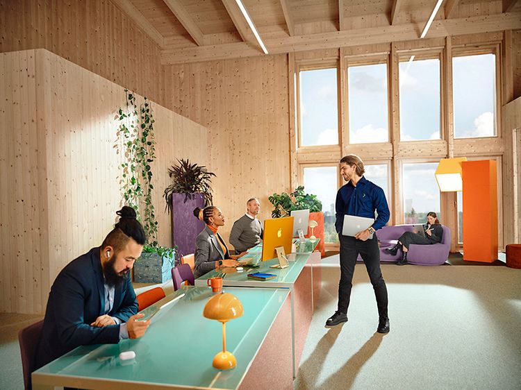 Flere ansatte på et kontor som bruker Apple produkter og En Elkjøp-ansatt
