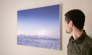SmarttelefElkjøp-kunde Jonas Karlsen beundrer bilde som henger på veggen, tatt med Samsung Galaxy S23 Ultra