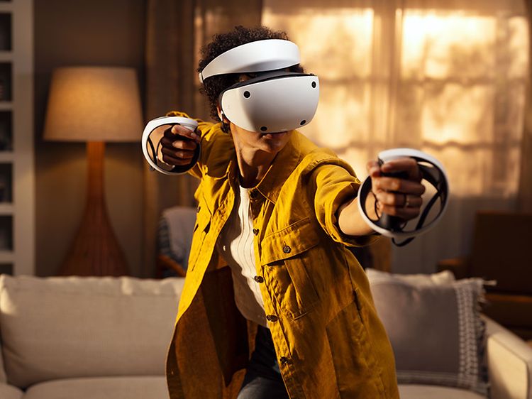Person som spiller med Playstation VR2-briller og kontroller i stua