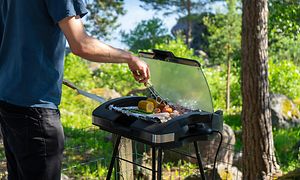 Mann lager mat med elektrisk grill på en sommerdag