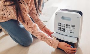 Woman changing water container of a small dehumidifier