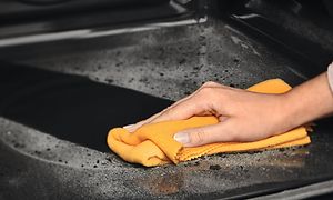 Pyrolytisk rengjøringsfunksjon og en hånd som rengjør innsiden av en Electrolux dampovn