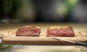 To saftige kjøttstykker på et skjærebrett og en kniv ved siden av