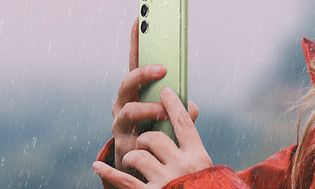 Kvinne holder en lysegrønn Galaxy A54 5G i regn