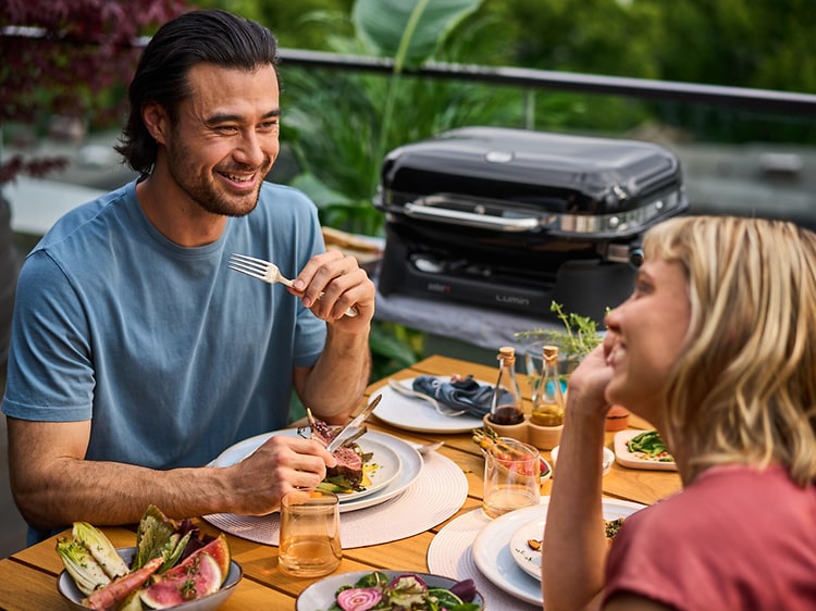 Couple eating outside in front of grill