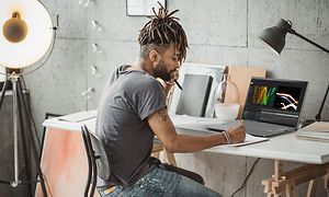 A guy wirking on his Acer Swift laptop with OLED screen at his desk