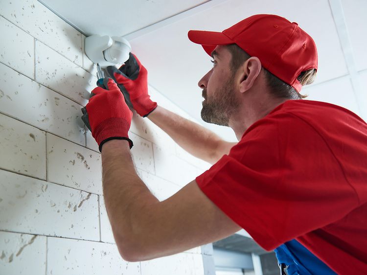 Man installing motion sensor on wall