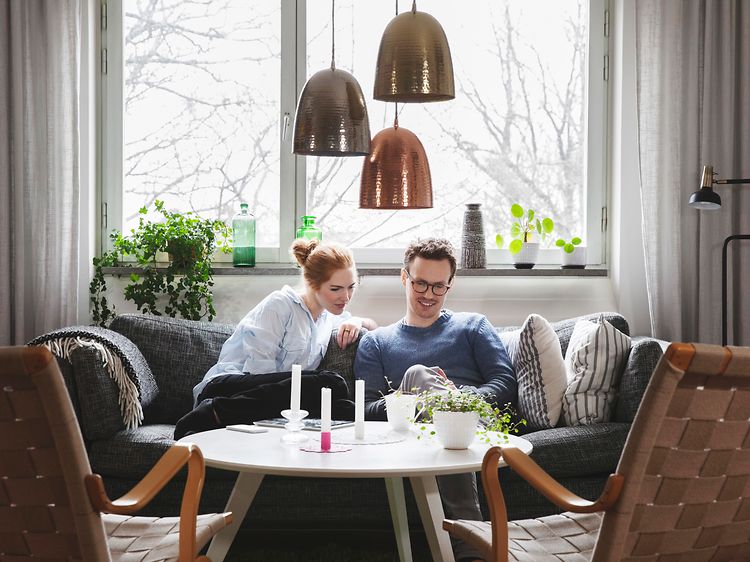 Couple sitting in sofa looking at phone