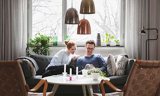 Couple sitting in sofa looking at phone