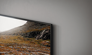 Nærbilde av et Samsung Q60C TV-hjørne på en grå vegg
