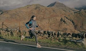 Cat S75 5G smarttelefon festet på armen til en kvinne som løper nær et fjell