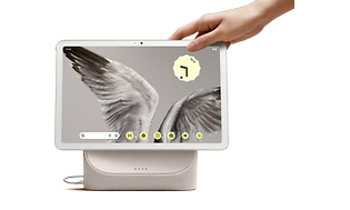 En hånd som strekker seg etter Google Pixel Tablet som viser et bilde av fuglevinger