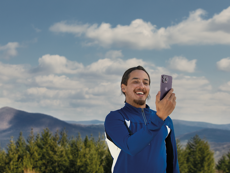 Mann som holder en iPhone 14 Pro med fjellandskap i bakgrunnen