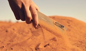Støvtett NokiaXR21-telefon blir plukket opp fra sand