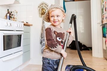 Kid with vacuum cleaner in a kitchen
