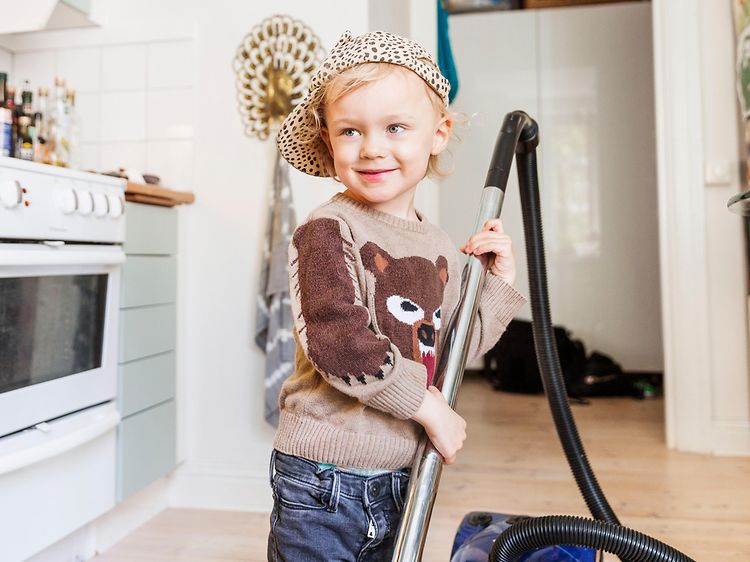 Kid with vacuum cleaner in a kitchen