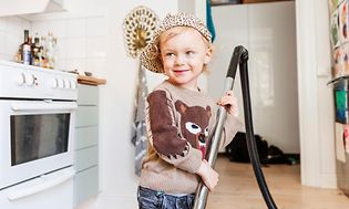 Kid with vacuum cleaner in a kitchen