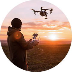Mann som flyr en drone på jordet på kveldstid under solnedgang
