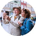 Eldre par står i en bygate og tar en selfie med mobilen sin