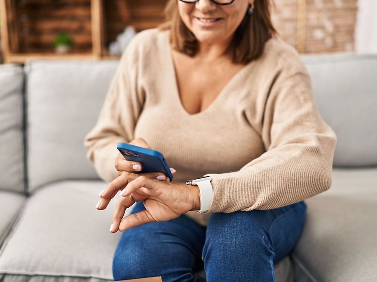 Telecom - Wearables - woman wearing a smartwatch with a smartphone in her hand