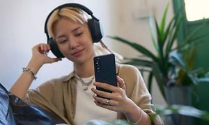 Ung jente lytter til musikk med Xperia 1 V og hodetelefoner