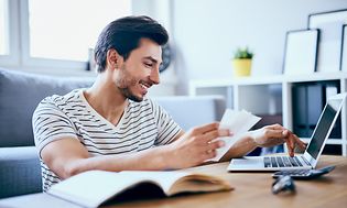 En mann som betaler regninger på PC-en