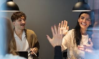 Kolleger som gir hverandre high-five i møte