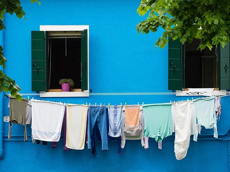 klær til tørk på tørkestativ foran blå vegg