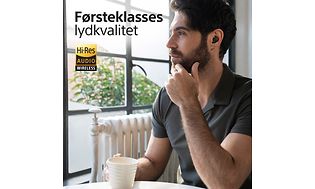 Mann som drikker kaffe med Sony WF-1000XM5 in-ear hodetelefoner i ørene
