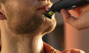 Nærbilde av en mann som trimmer sitt skjegg med Philips OneBlade Pro 360
