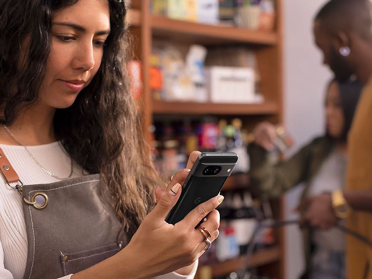 Woman in a store holding a Google Pixel 8