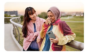 Two women laughing and one is holding a Google Pixel 8