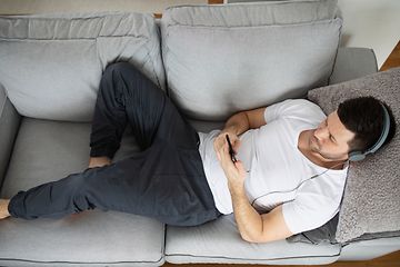 Man on a couch with headphones listening to music