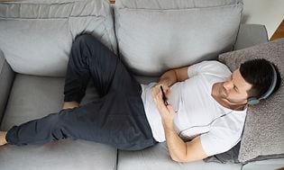 Man on a couch with headphones listening to music