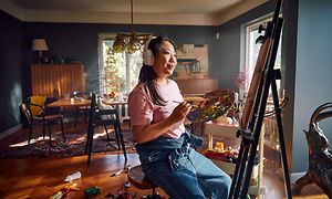 Woman with headphones painting in a living room