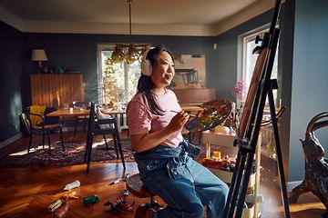 Woman with headphones painting in a living room