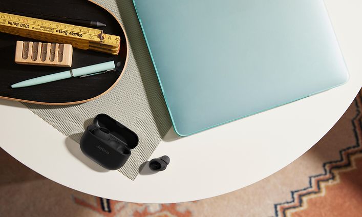 Jabra Elite 10 ved siden av en bærbar-PC