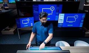 Elkjøp Bedrift Key Account Manager Waqas Ahmad står foraen tv-skjerm i ulike størrelser