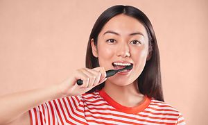 Kvinne pusser tenner med Philips One elektrisk tannbørste