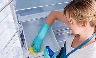 Kvinne vasker grønnsaksskuff i kjøleskap 