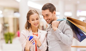 Par er på shoppingtur hvor hun viser han noe på mobilen